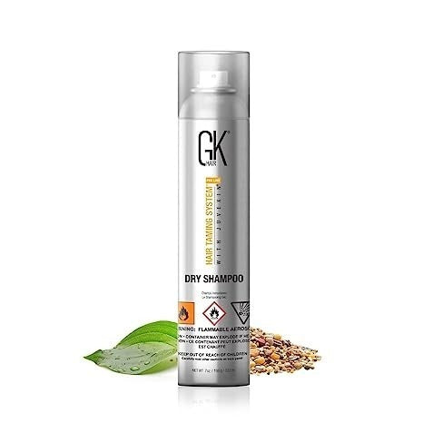 GK Hair Dry Shampoo silver aerosol can, angled view with a green leaf and scattered seeds
