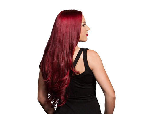 A woman with long, vibrant red hair styled in loose waves, wearing a black sleeveless dress, viewed from the back.