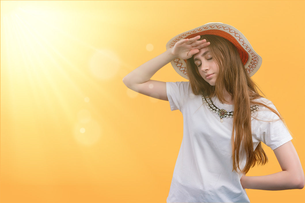 Woman in a straw sun hat shielding her eyes from bright sunlight, a reminder to protect hair from the sun