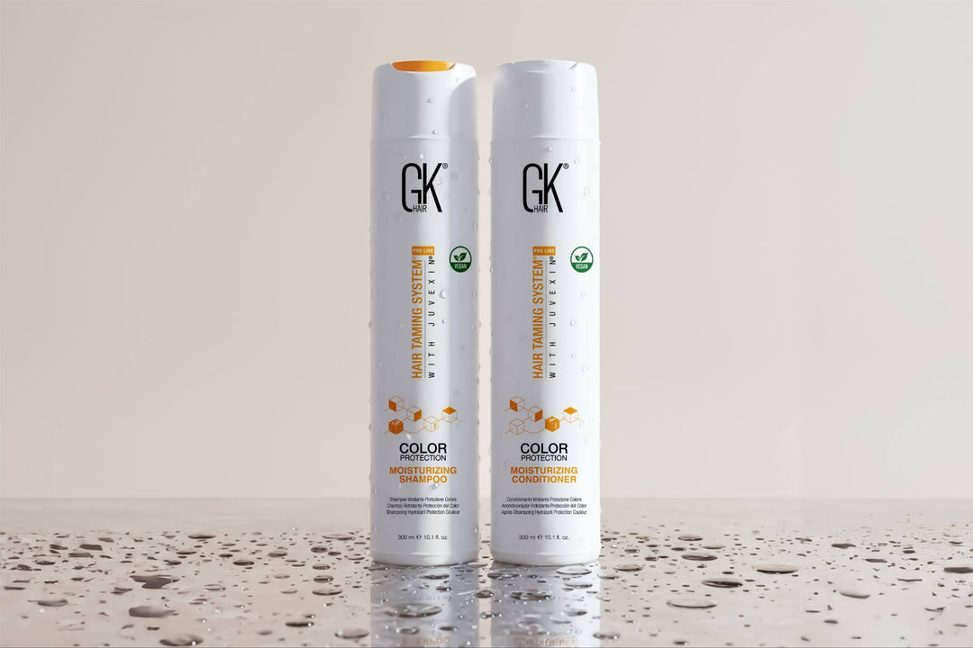 GK Hair Color Moisturizing Shampoo and Conditioner, standing on a surface with water droplets, showcasing a sleek design.